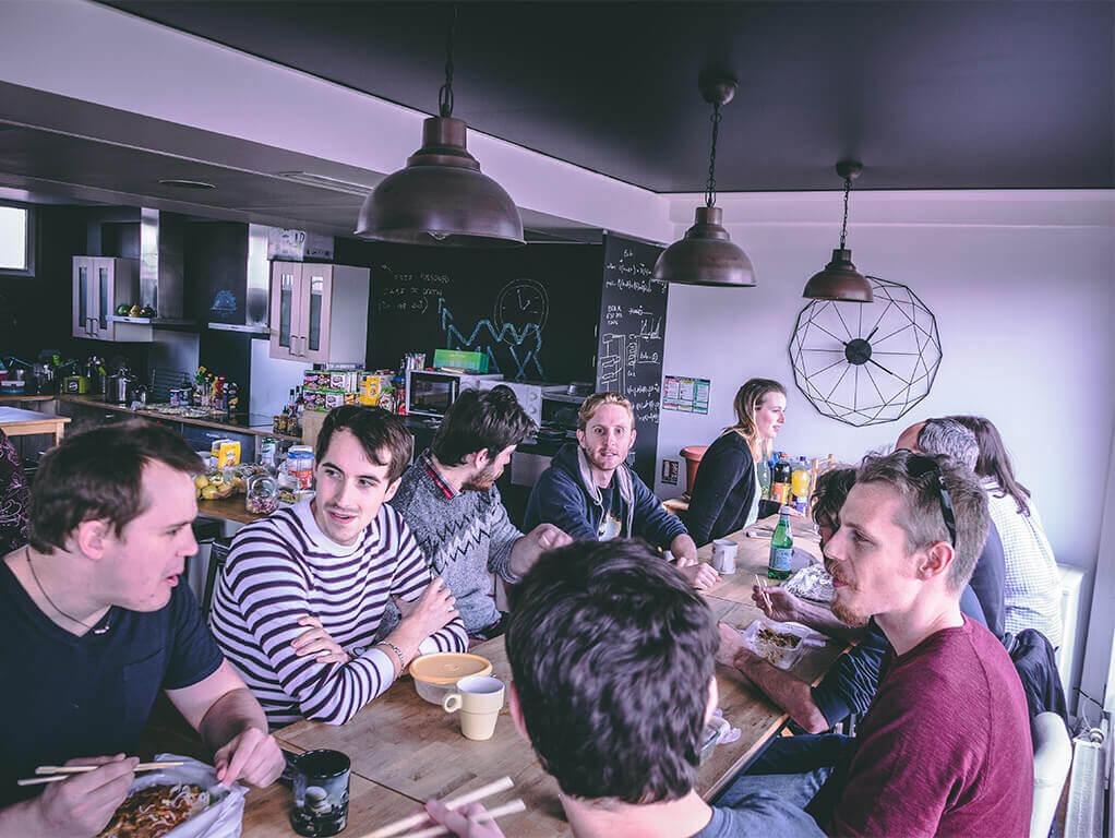 A bunch of co-workers seat at the table in the kitchen